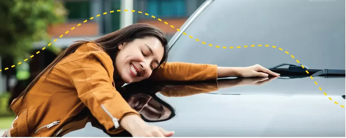 Happy woman leaning over bonnet of a car