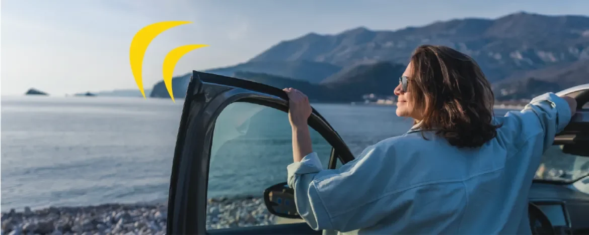 Woman stood outside car, looking at the sea