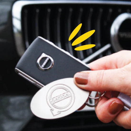 hand holding car keys in front of car