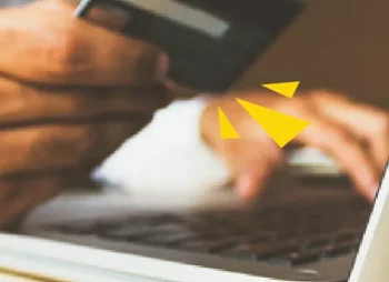 Hand holding credit card over laptop