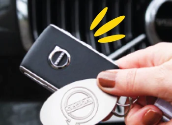 hand holding car keys in front of car